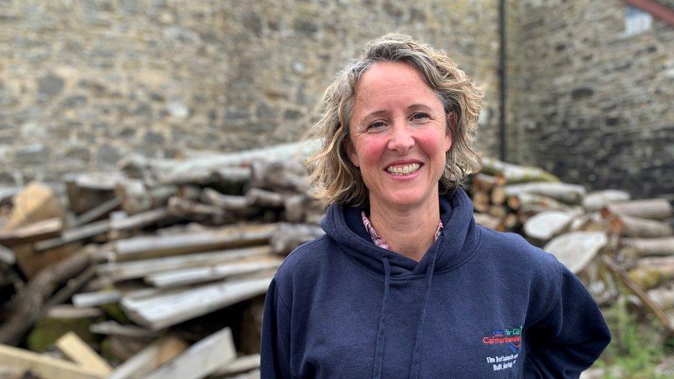 Nell Hellier standing in front of timber and a stone wall