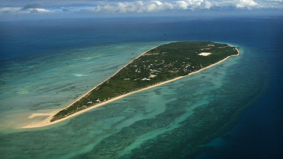 A small island surrounded by clear blue sea.