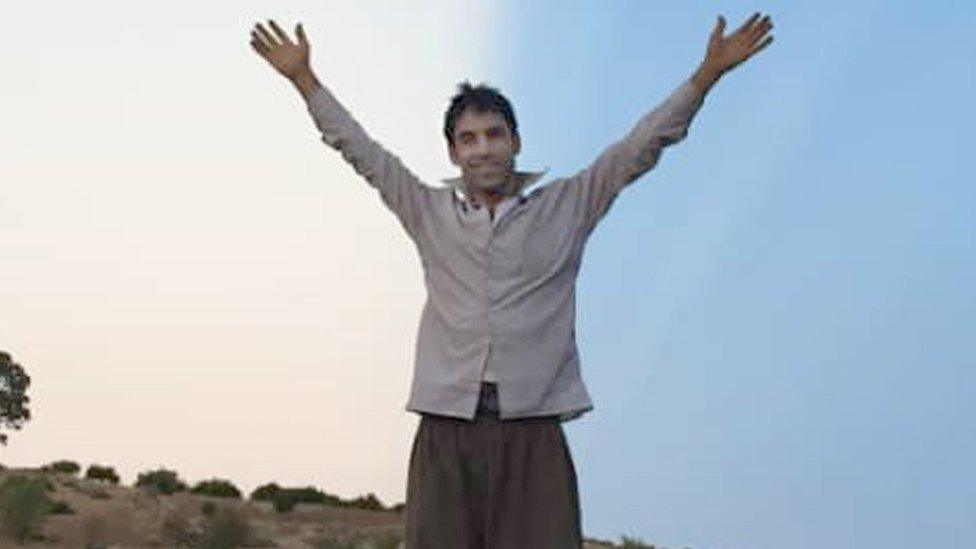 Vahid Afkari standing on the roof of a car with his arms in the air