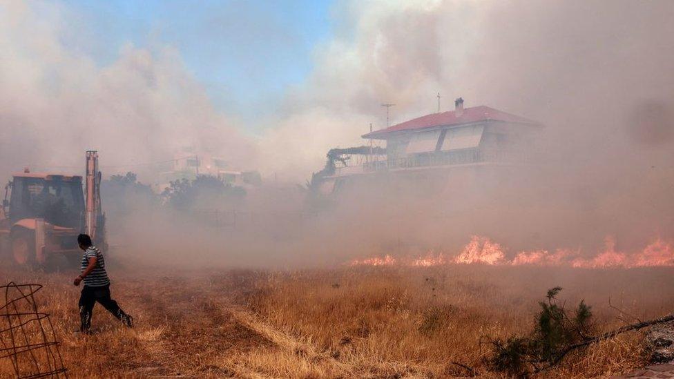 A man runs from flames in a field.