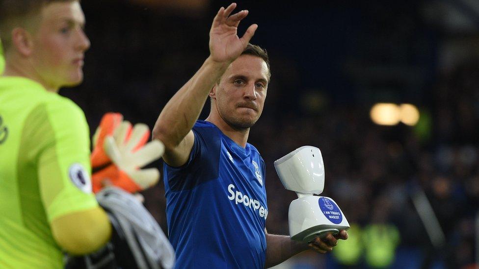 Everton captain Phil Jagielka carries the robot onto the pitch