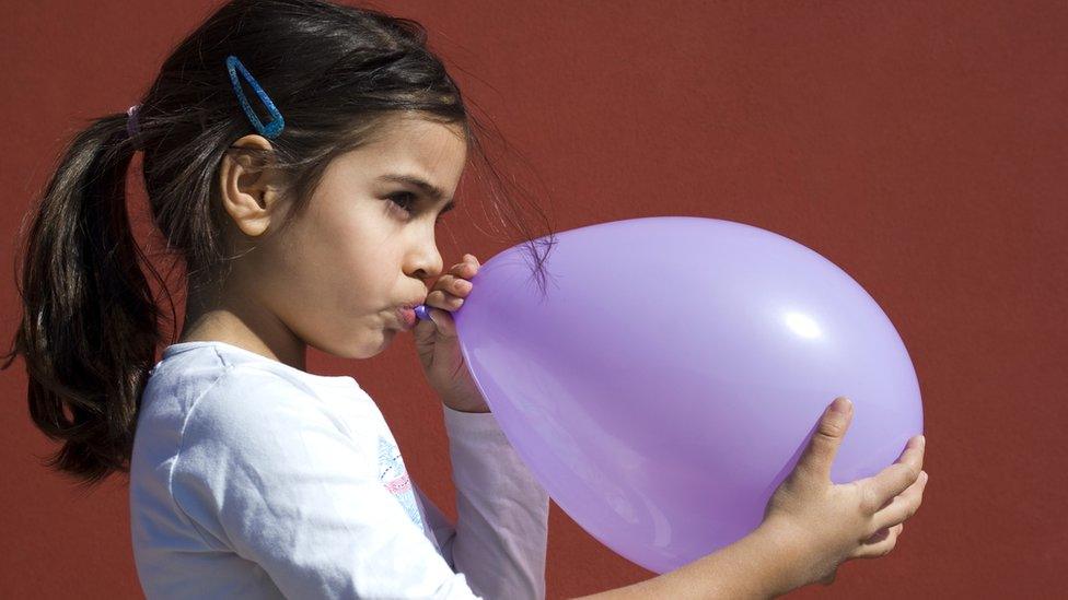 Girl blowing up a balloon