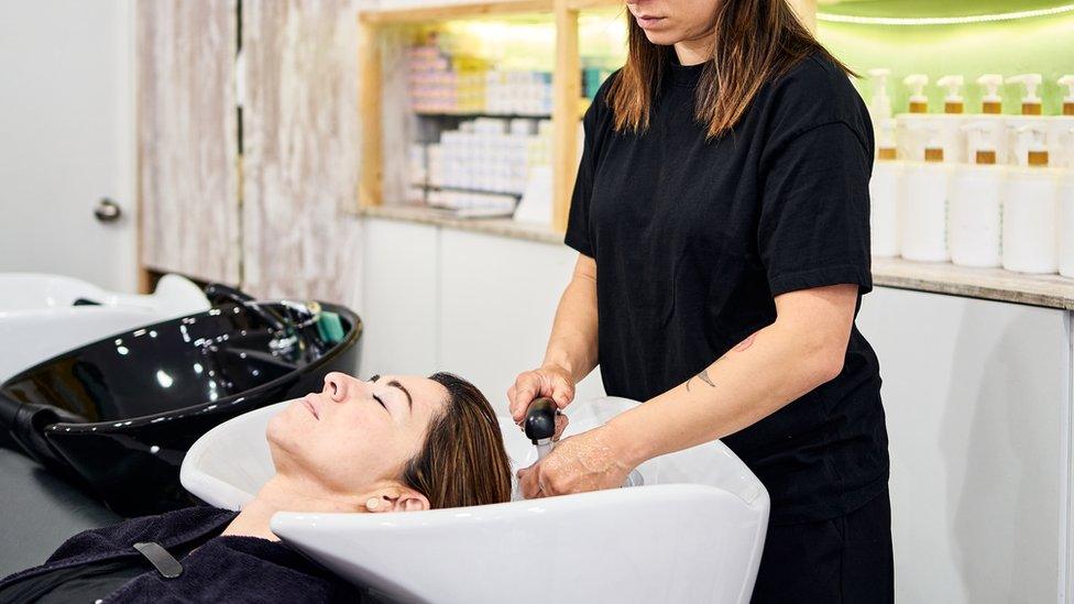 Salon worker washing woman's hair