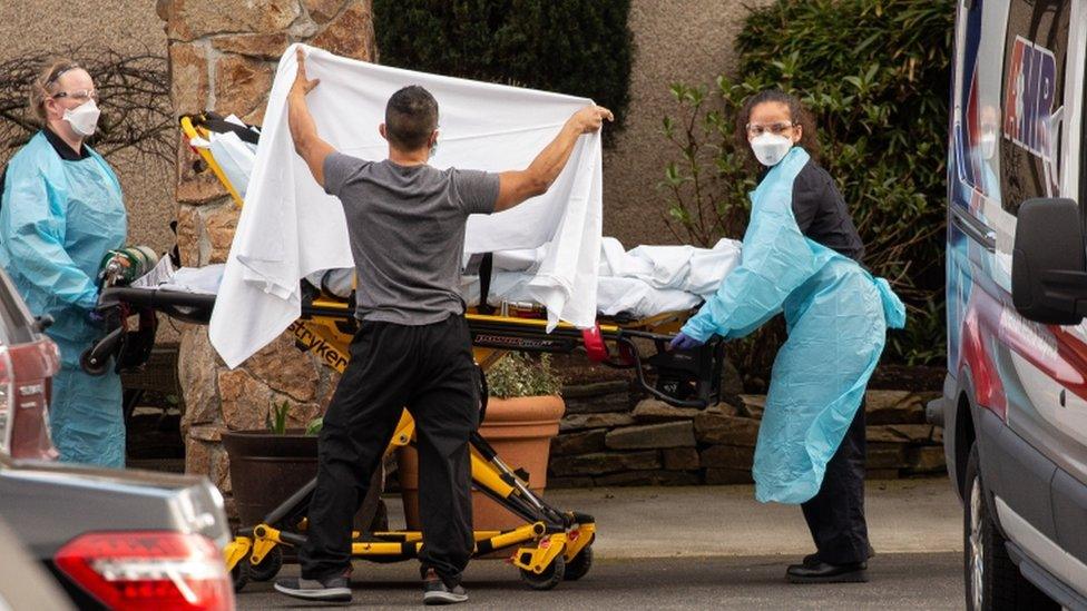 Healthcare workers transport a patient on a stretcher into an ambulance at Life Care Center of Kirkland in Kirkland, Washington