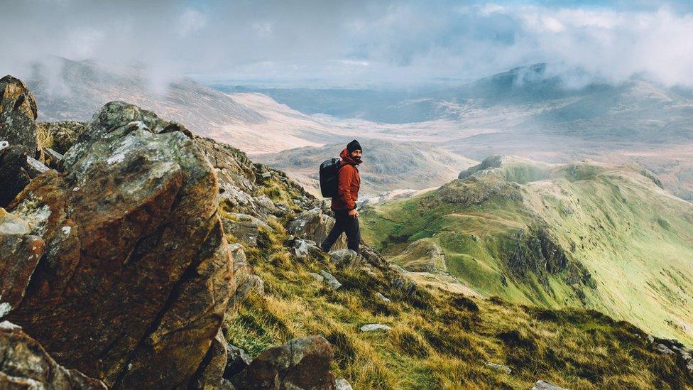 A hiker wearing a backpack, making his way down from the summit of Snowdon on a beautiful autumn day