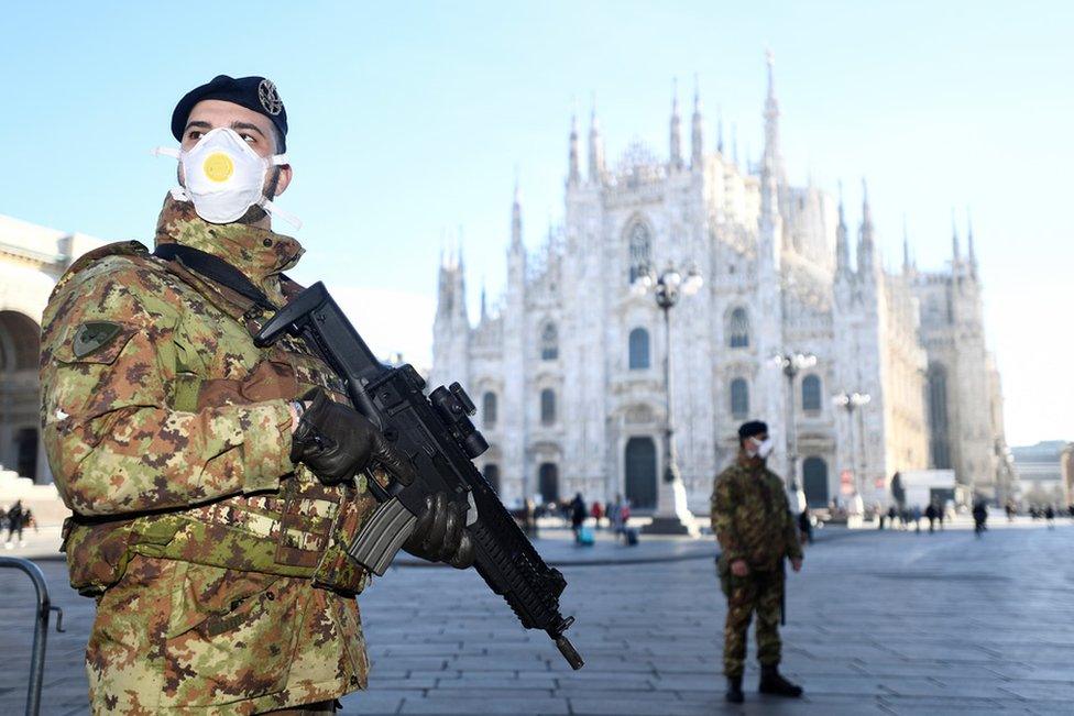 Military officers wearing face masks stand outside Duomo cathedral, closed by authorities due to a coronavirus outbreak, in Milan. 24 February