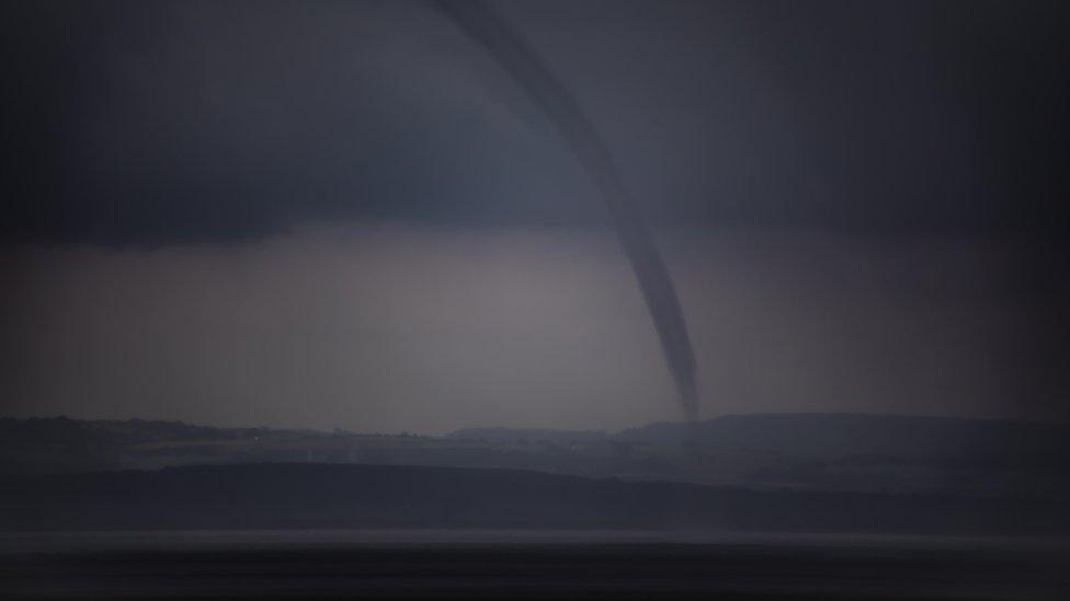 Long tornado shaped cloud over water