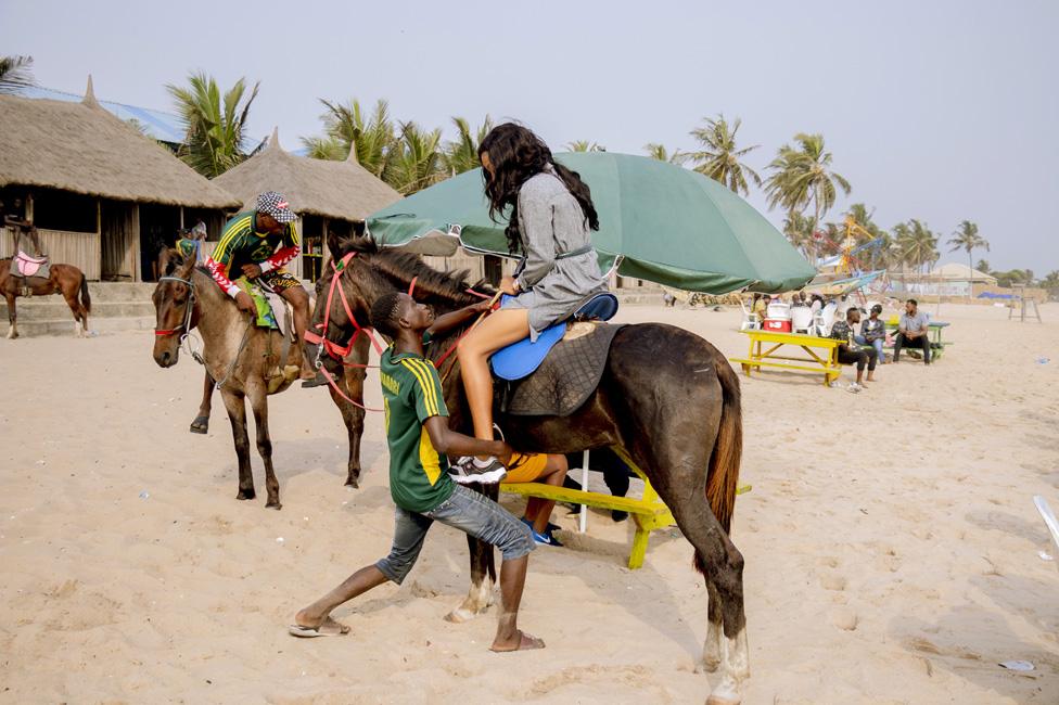 Woman being helped onto a horse