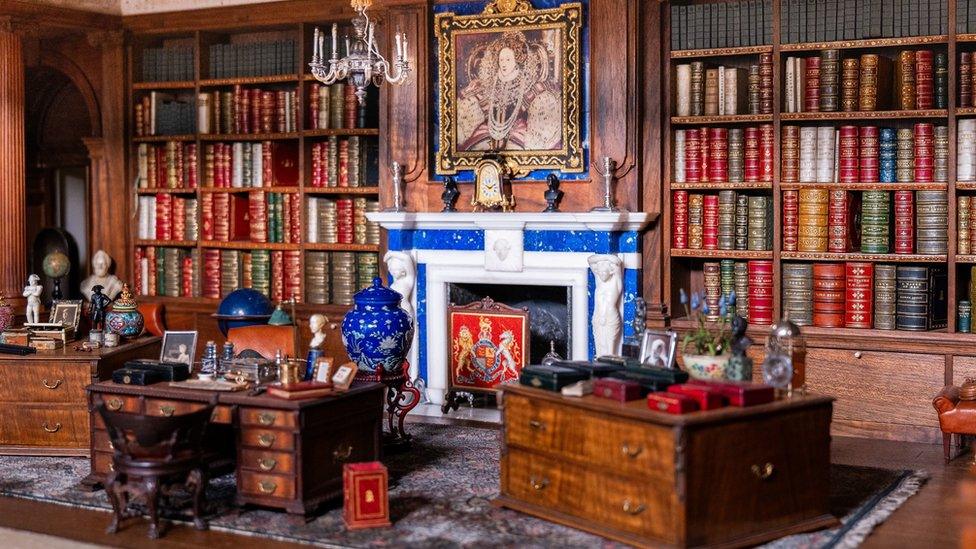 miniature library with shelves stacked with tiny books and a fireplace