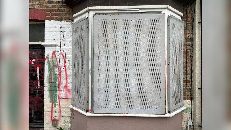 The boarded-up windows of the property