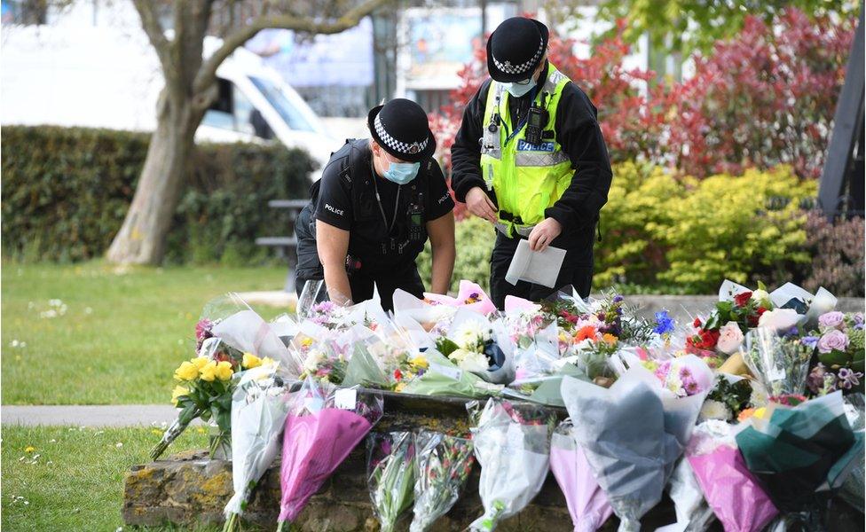 Police officers lay flowers at the scene