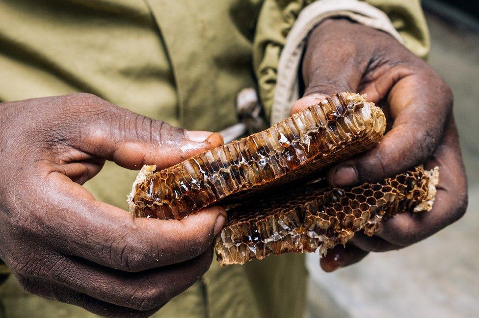 A man holds honey in his hand