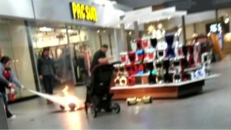 Hoverboard on fire in a mall as someone uses a fire extinguisher on it