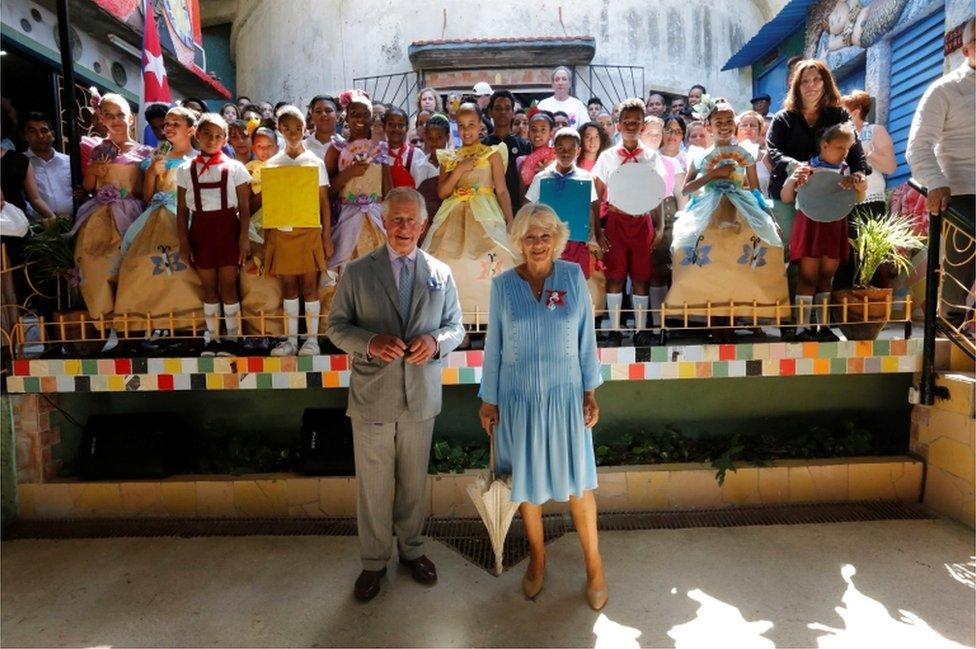 Prince Charles and Camilla pose in front of the children dressed in colourful costumes