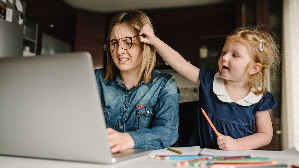 Child bothering woman trying to work on laptop