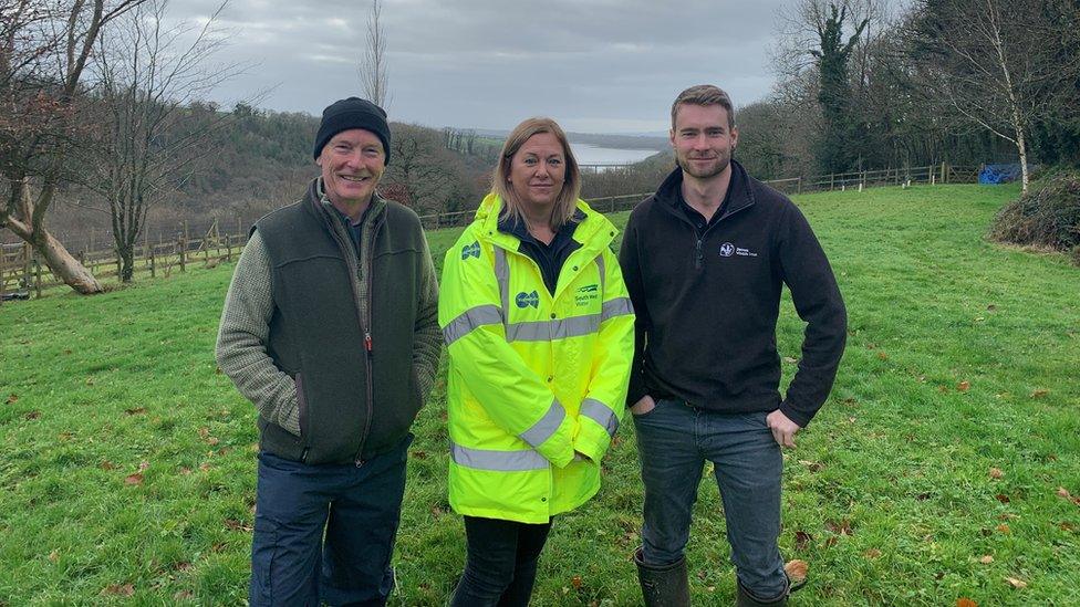 Two men and a woman standing in field