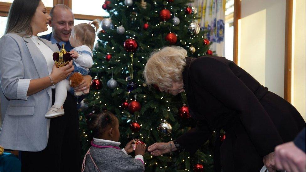 Queen Camilla helps a young patient hang ornaments on a Christmas tree during a visit to meet children, families and staff at Childrens Hospice South West's (CHSW) Charlton Farm children's hospice, in Bristol.