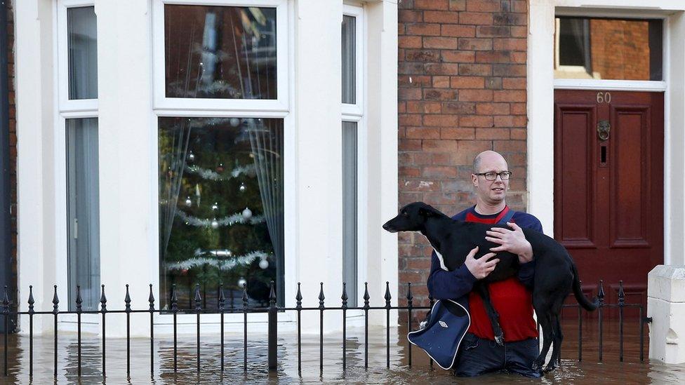 A man holds his dog as he wades through the flooded streets in Carlisle. Lots of people are having to carry their pets out of the their flooded homes to safety.