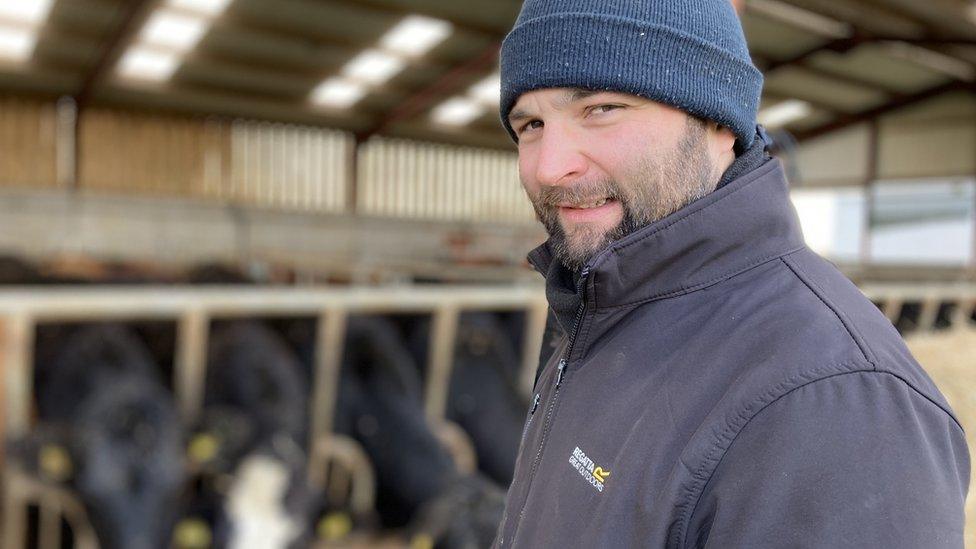 Jonathan Blair standing in front of some cows