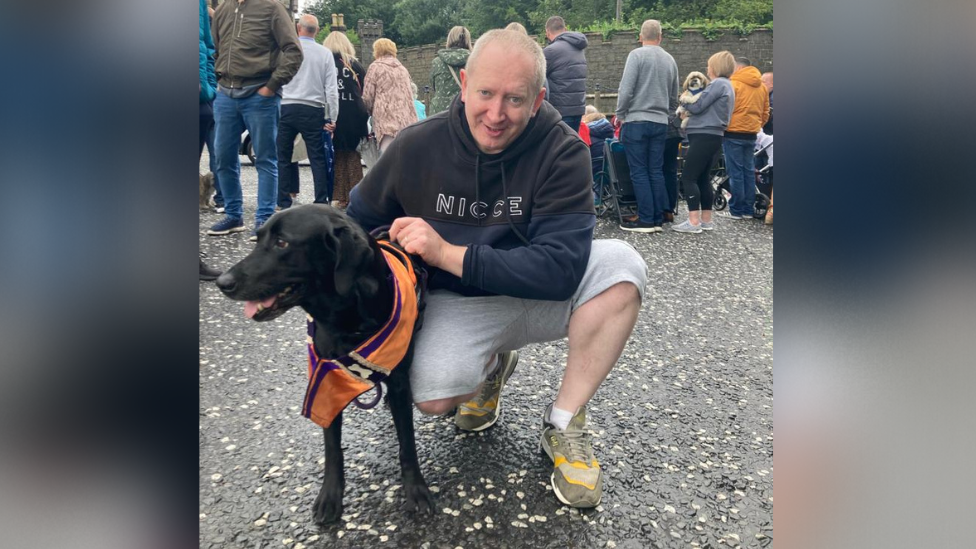 Man with dog wearing orange sash