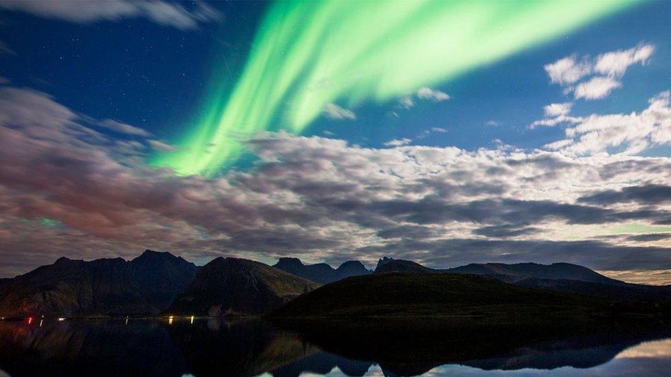 Northern lights over water and hills