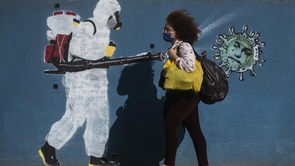 Woman walks past street mural in Brazil