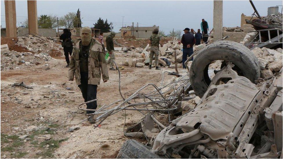 Rebel fighters walk through rubble following an alleged bombing by IS in Marea (image from April 2015)