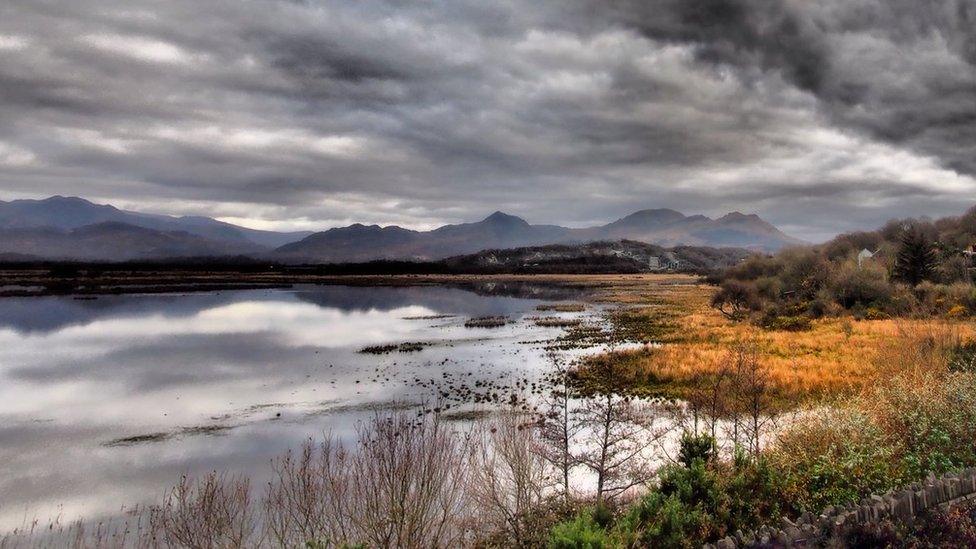 Mae'r cymylau'n edrych yn ddu uwchben cors Porthmadog