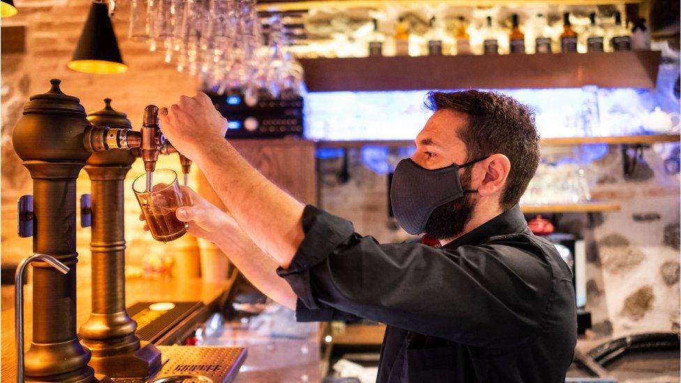 Bartender wearing face mask pulls a pint