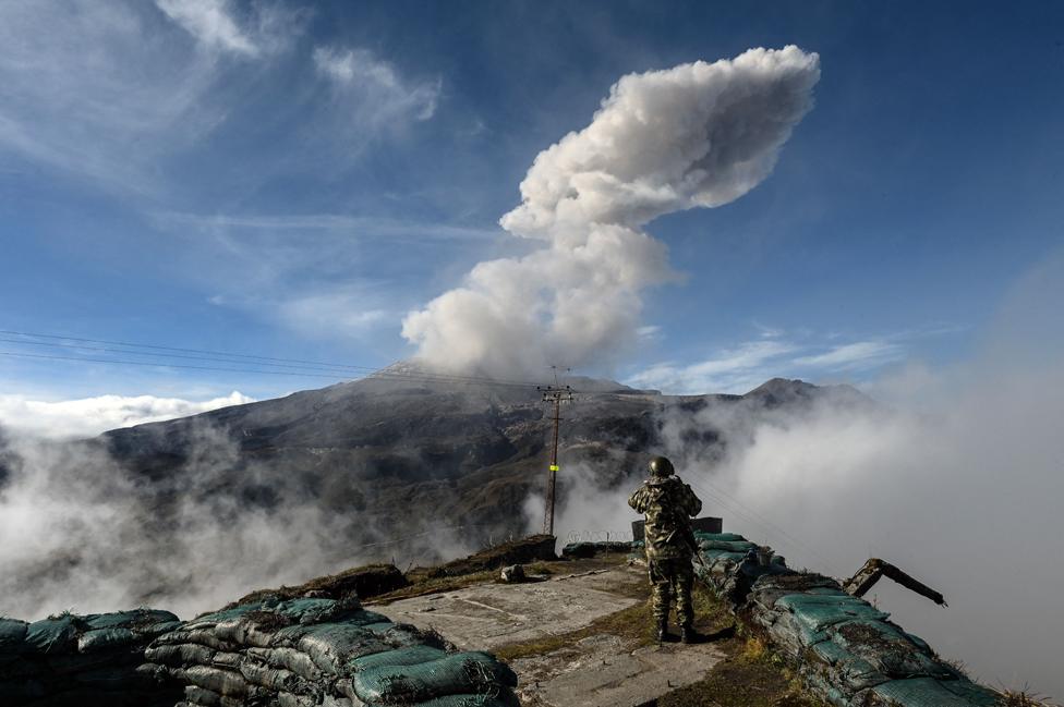 Colombian soldier watches the Nevado del Ruiz volcano as it emits a cloud of ash