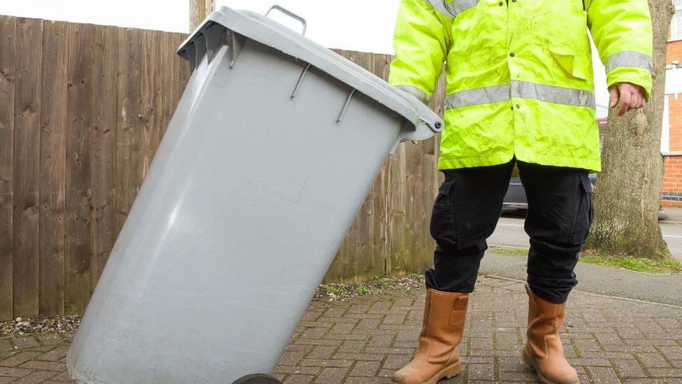 A Binman taking a grey wheelie bin