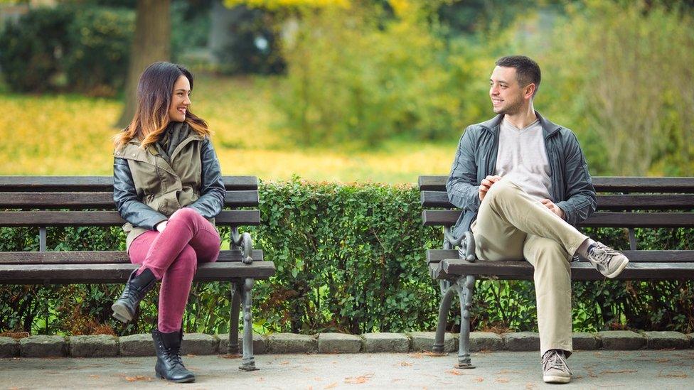 People talking to each other on a park bench