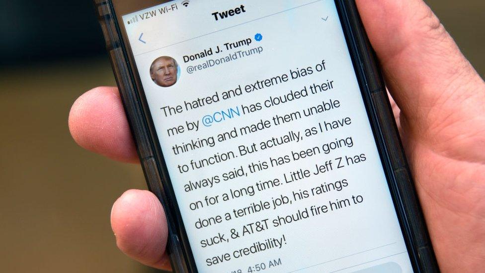 A man holds up his phone displaying a tweet by US President Donald Trump attacking CNN