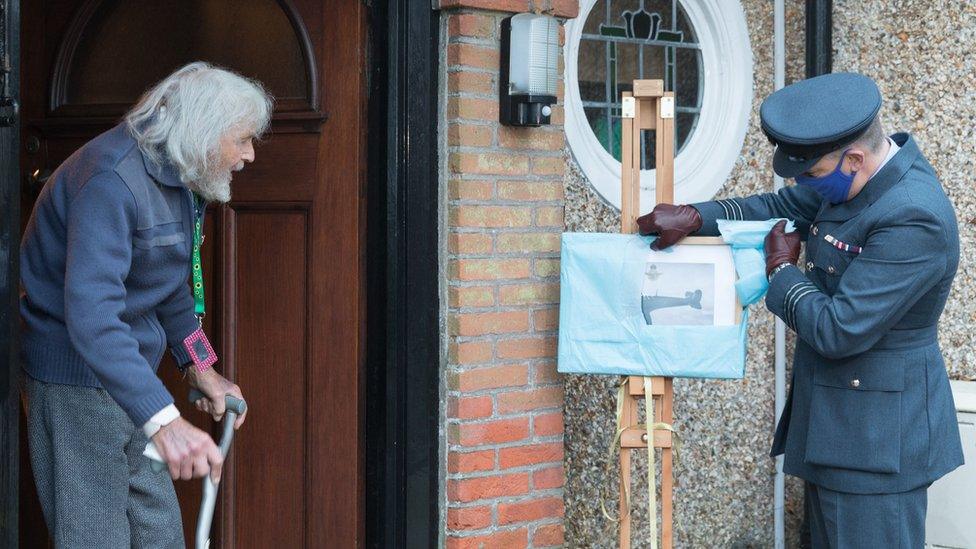 Dr Edmund James at front door being presented with Spitfire photograph