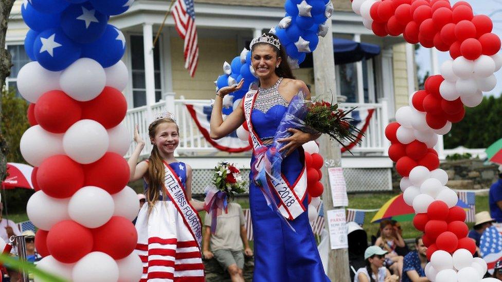 Little Miss fourth of July and Miss Fourth of July wave from their parade float in Bristol, Rhode Island