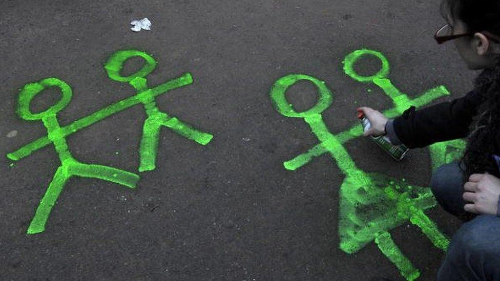 A girl spray paints figures of male and female couples in front of the Congress building during a demonstration supporting a gay marriage bill, while Senators discuss said bill for same sex marriage in Buenos Aires on 14 July, 2010.