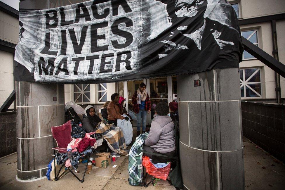 Protesters camp outside a police station under a banner that reads "Black Lives Matter"