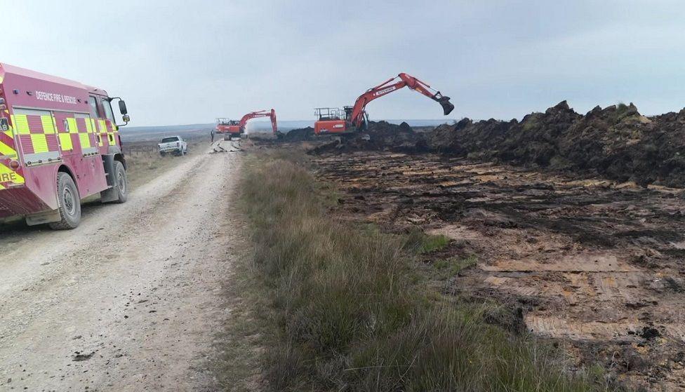 Diggers and fire vans working to put firebreaks into the ground