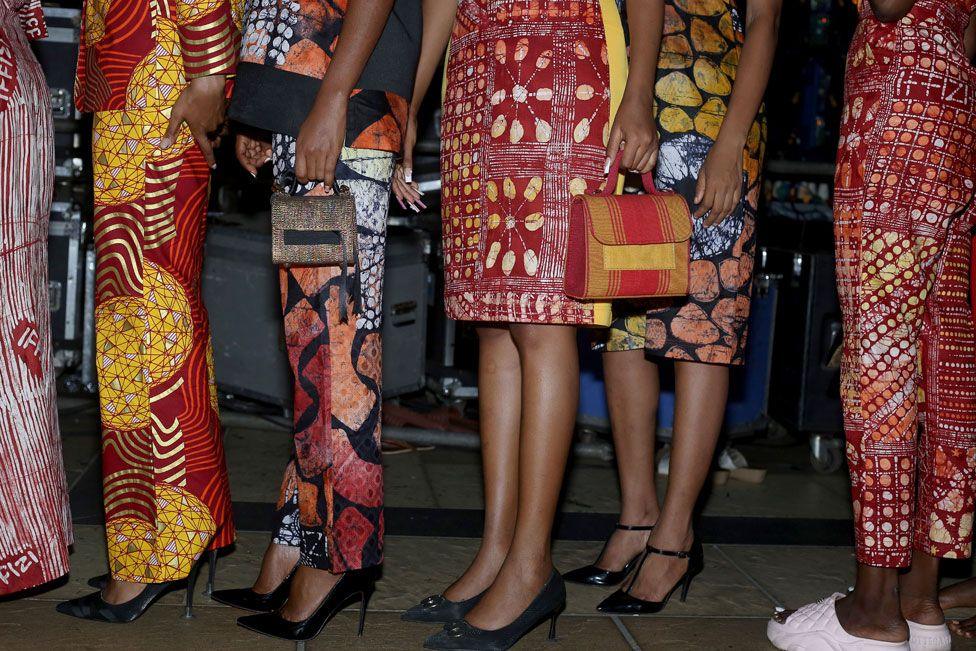 Women stand close together in a queue. They are only visible from the waist down. They wear knee-length skirts and straight-leg trousers. In Lagos, Nigeria - Saturday 7 December 2024
