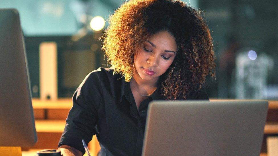 Woman looking at computer and phone