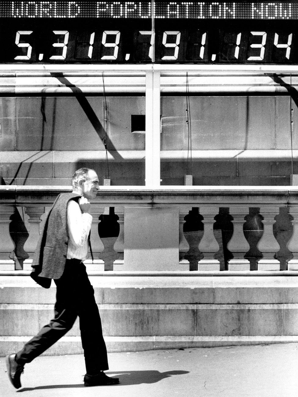 Paul Ehrlich walks past a population counter in Australia in 1991