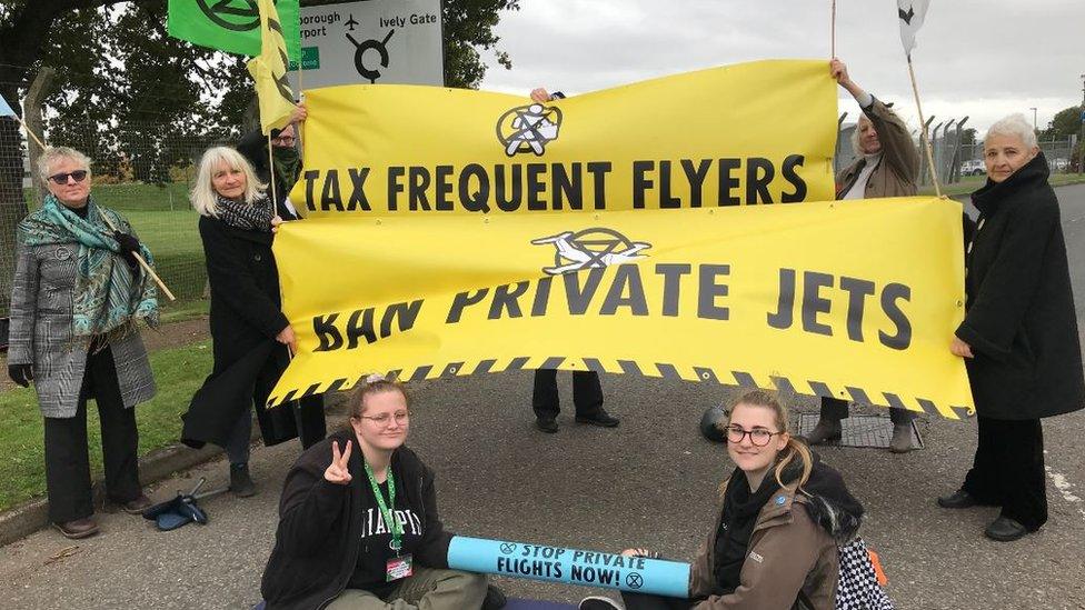 XR protesters with signs saying 'tax frequent flyers' and 'ban private jets'