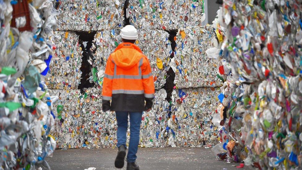 An employee walks through plastic wastes waiting to be recycled