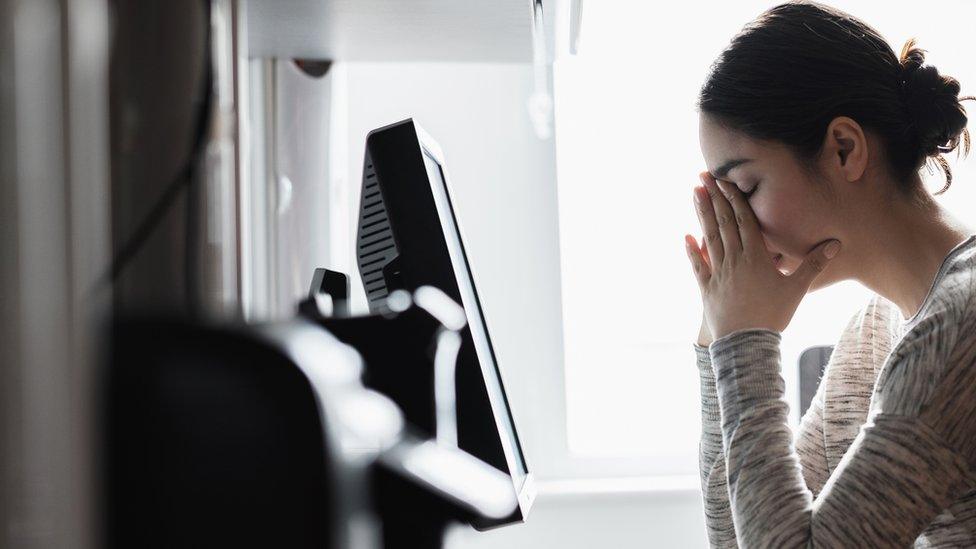 A woman sitting at a computer looking really stressed