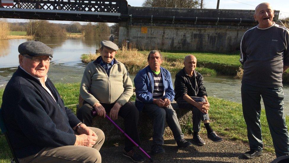 A group of French fishermen sitting by a river