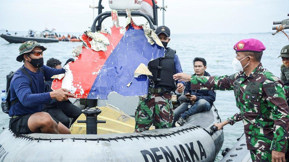 Indonesian Navy personnel carry debris believed to be from the Sriwijaya Air SJ-182 plane,