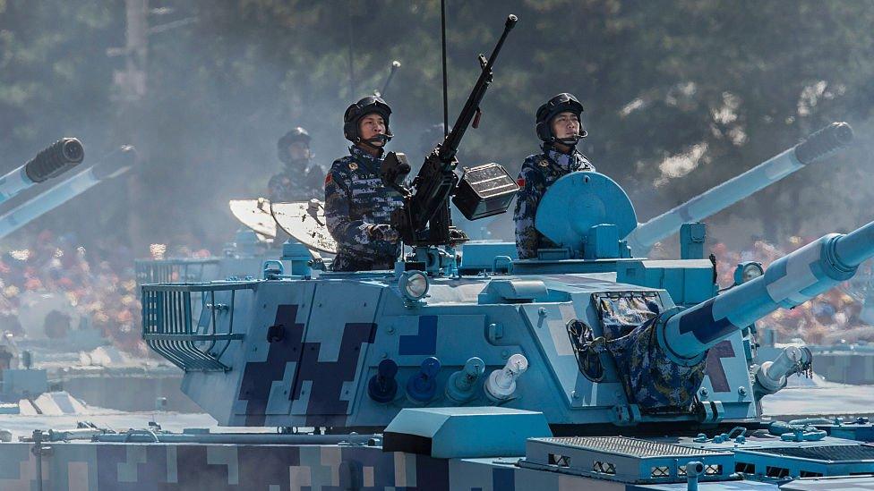 Chinese soldiers ride in tanks as they pass in front of Tiananmen Square and the Forbidden City