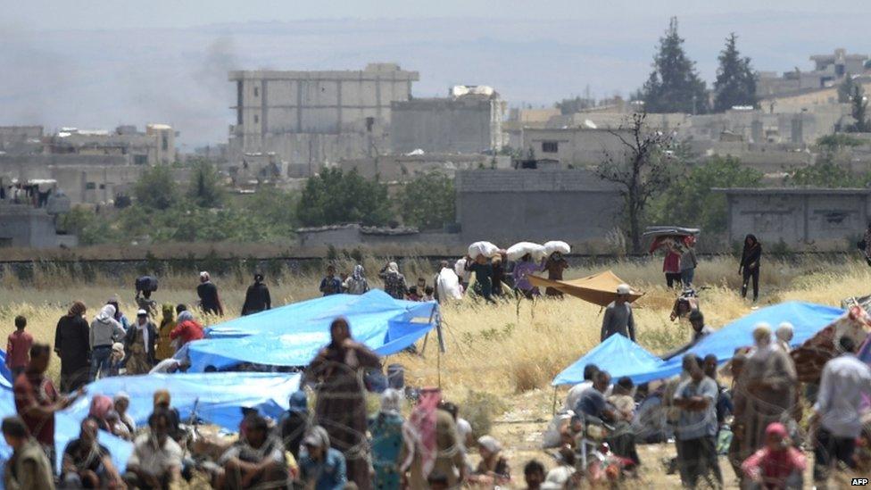 Civilians head towards the Syrian town of Kobane from Turkish territory, 27 June