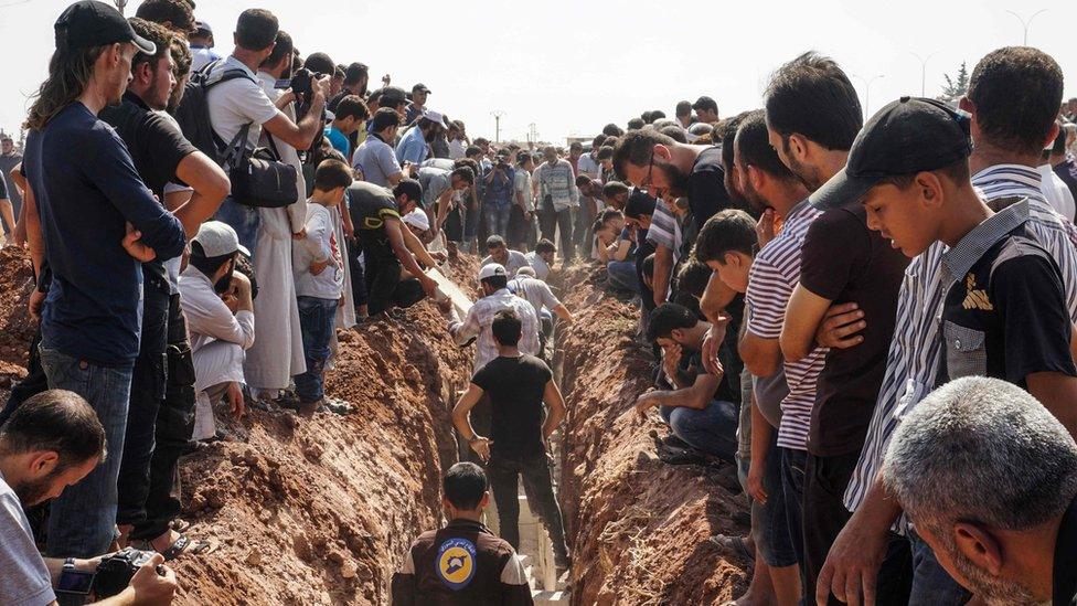 Members of the Syrian civil defence volunteers, also known as the White Helmets, bury their fellow comrades during a funeral in Sarmeen