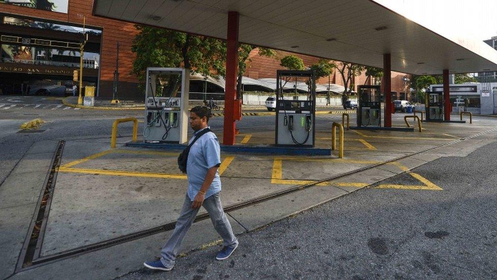 A man walks past an abandoned petrol station